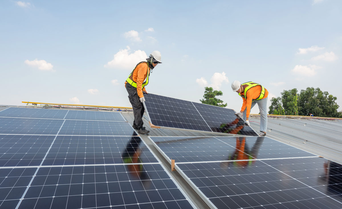 works-installing-solar-panels Two workers installing a solar panel on a roof