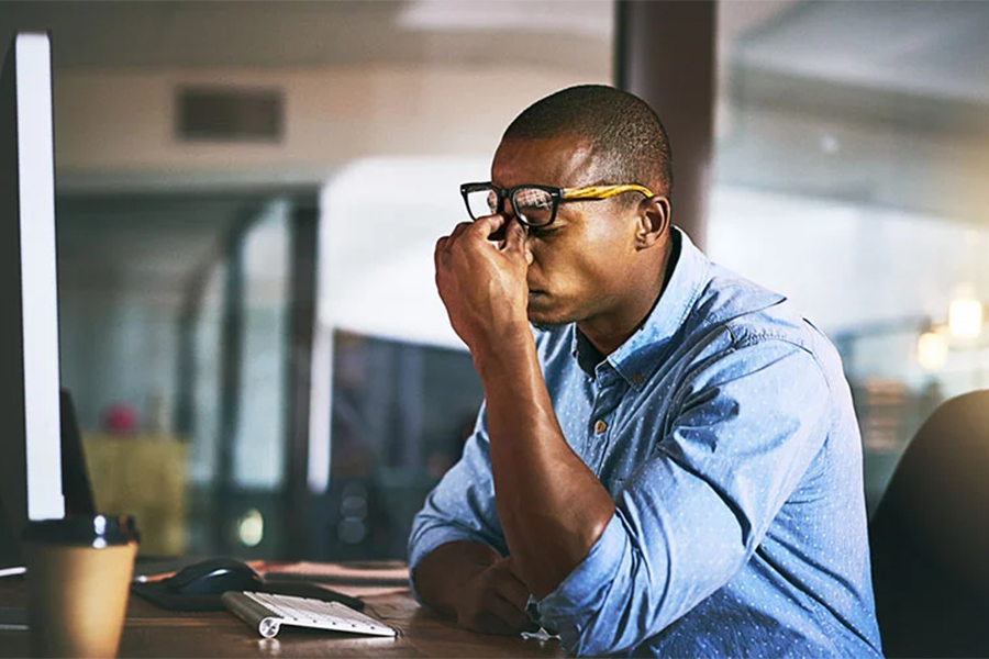 Man sits at a desk looking frustrated.