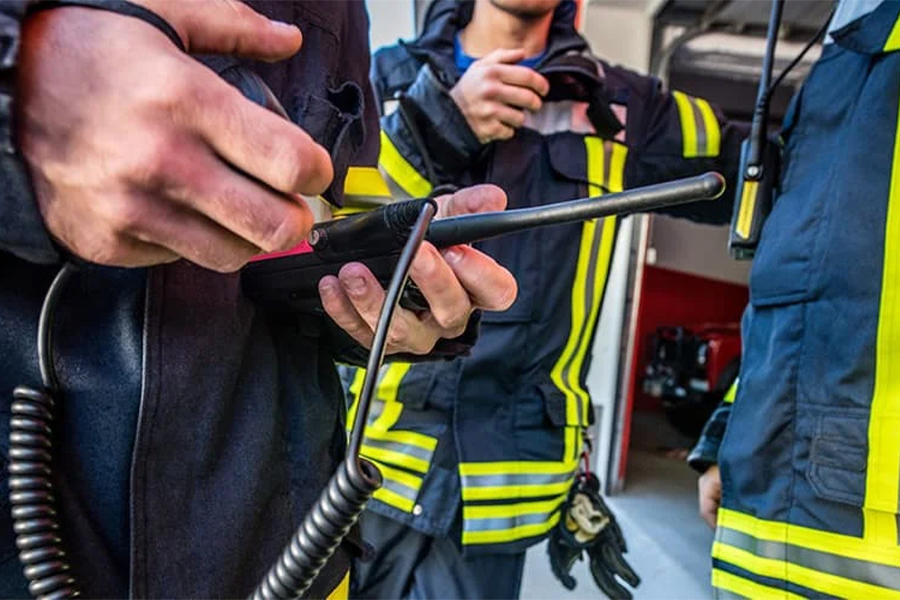 Close up image of a firefighter holding a walkie talkie.