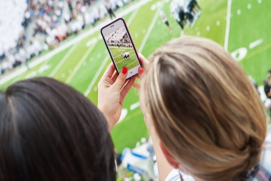 Woman recording a sport event on her phone.