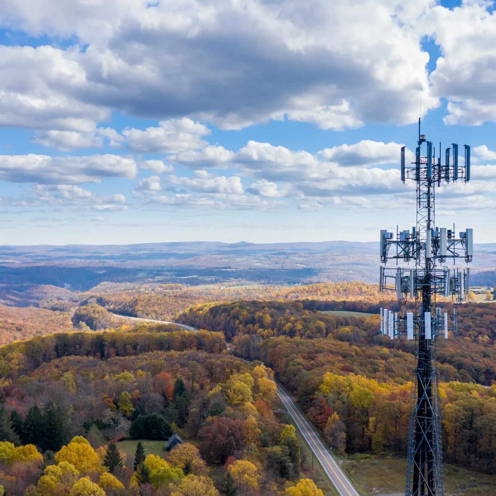 Cell tower with a fall landscape of trees in the background