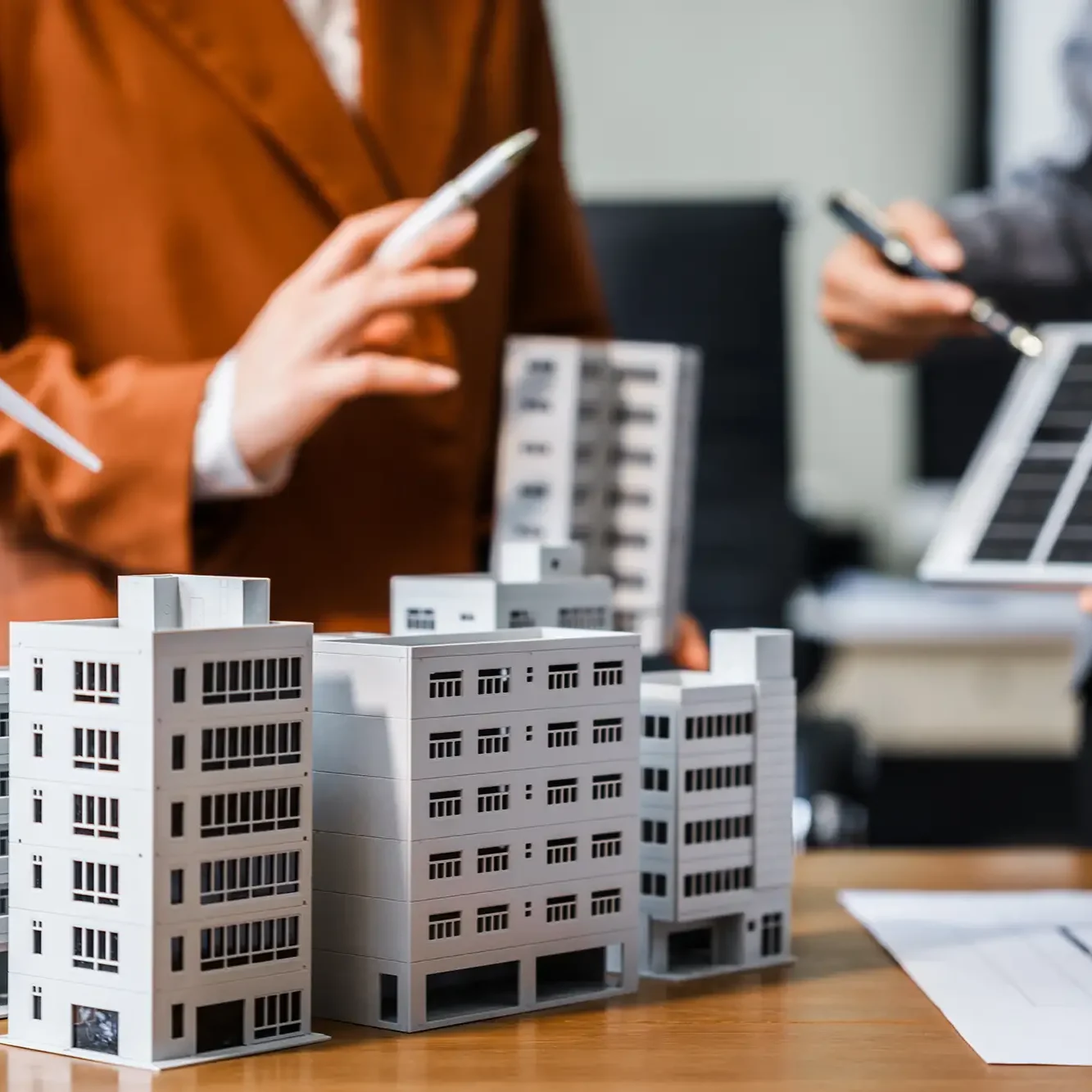 people talking about a desk with a building in the middle of the desk
